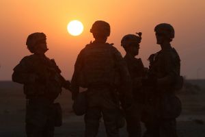 American soldiers at US army base, standing in front of a sunset.