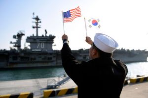 A ROK sailor waves flags in front of an aircraft carrier