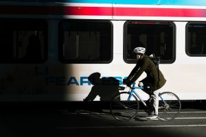 A person on a bike rides by a bus in the city.