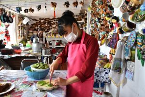 two women prepare food in mexico wearing masks 