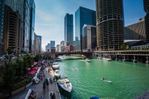 A view of the Chicago Riverwalk, along the Chicago River, with skyscrapers in the background.