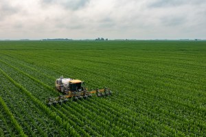 A tractor plows a green field.