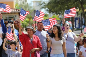 People of various ages wave American flags