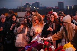 People lay flowers and light candles next to the Crocus City Hall concert venue in Moscow