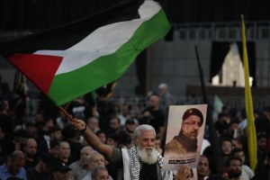 A Hezbollah supporter waves the Palestinian flag during the funeral procession of top commander Fouad Shukur who was killed by an Israeli airstrike