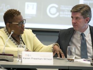 Two people talk while sitting at a table during an event 