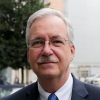 Daniel Gustafson looks into the camera with a slight smile from the shoulders up, wearing a dark blue suit and tie.