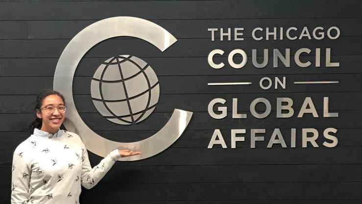 Next Generation intern Meg in front of the Council's logo wall. 