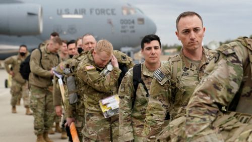 Military personnel from the 82nd Airborne Division and 18th Airborne Corps board a C-17 transport plane for deployment to Eastern Europe