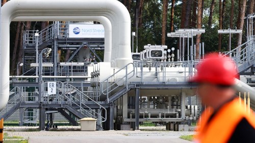 A person in construction gear walks past a gas tank