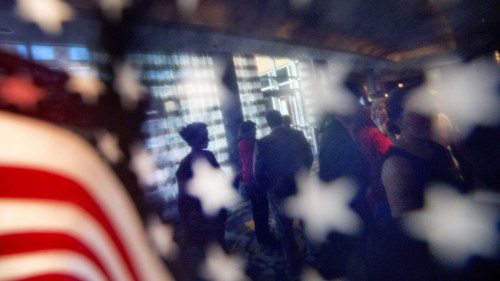 an American flag with people standing behind it