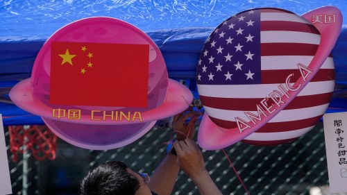 A vendor sets up foods and beverages at a booth displaying planets shaped of China and American flags