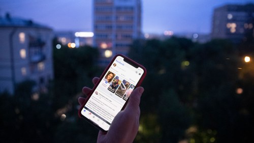 a person holds a phone open to Facebook