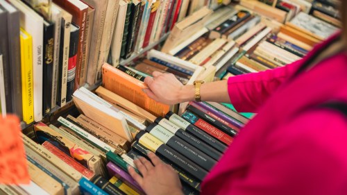 A photo taken from above shows a person browsing a table and shelf of foreign-language books