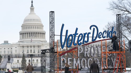 a sign that says voters decide protect democracy in front of the US Capitol