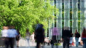 Blurred image of people walking outside a high rise building