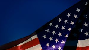 American flag, waving in front of a dark blue sky