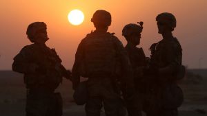 American soldiers at US army base, standing in front of a sunset.