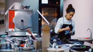 A chef prepares food amongst equipment in a kitchen