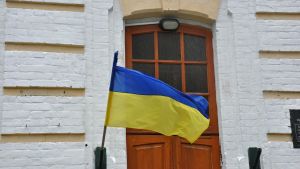 Flag of Ukraine waving in front of a wooden door.