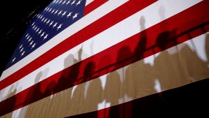 Shadows of people standing in front of an American flag