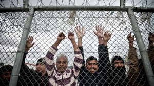 Immigrants stand behind a fence at a detention centre in the Amygdaleza suburb of western Athens