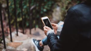 A person with their back to the viewer looks at their mobile phone.