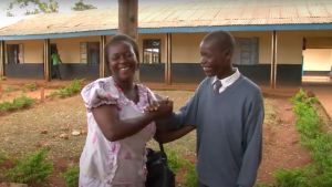 A woman and her son shake hands and laugh