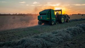 A farmer rides a tractor through a crop while harvesting