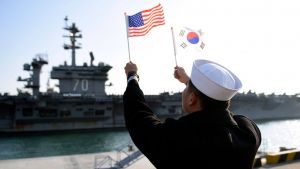 A ROK sailor waves flags in front of an aircraft carrier