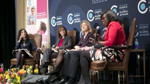 Four women talk on stage, with one talking into a microphone