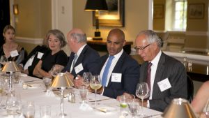 Members chat while seated at a table during a private dinner event.