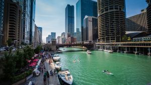 A view of the Chicago Riverwalk, along the Chicago River, with skyscrapers in the background.