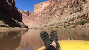 A person's shoes with a view of a river and rocky canyon in the background