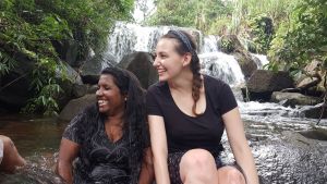 Two people laugh while sitting in front of a waterfall 