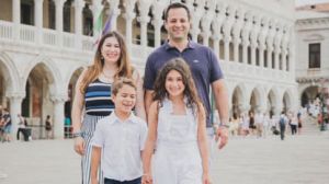 Four people walk in front of old stone buildings in Venice