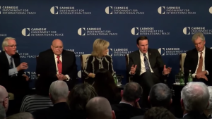 Five people sit in chairs onstage during an event