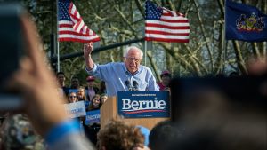 Bernie Sanders speaking at a podium to a crowd of supporters