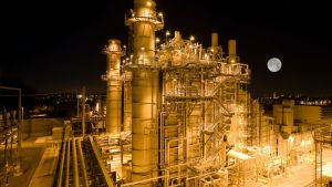 An aerial view of a power plant at night, with the moon in the background