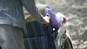 A person pushes someone in a wheelchair