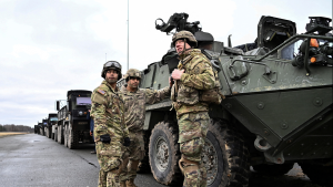 American soldiers stand in front of an armored tank