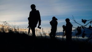 Silhouettes of soldiers walking up a hill.