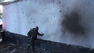 "A man stands next to a building damaged by recent shelling during border clashes with Azerbaijan"