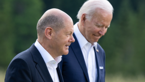 Scholz and Biden, with Scholz in the foreground and Biden slightly blurred in the background, walking outside. 