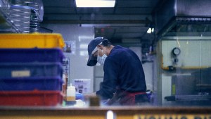 a person wearing a mask works at a pizza shop