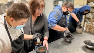 Three students participating in the CRYP Garden Club learn how to grind berries.