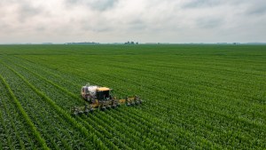 A tractor plows a green field.