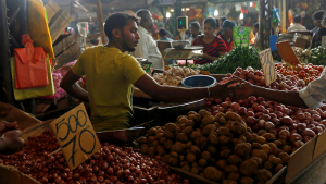 A man at a food stall hands change to a customer in Sri Lanka.