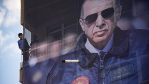 Youngsters stand next to giant election billboard of Turkish President Recep Tayyip Erdogan