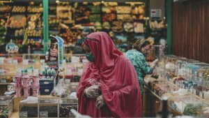 A woman stands in a grocery store examining food options.